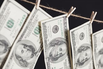 Hundred dollar bills hanging from a clothesline on a dark background
