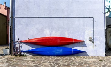 Two sea kayaks on a blue house