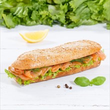 Roll sandwich wholemeal baguette topped with salmon fish square on wooden board