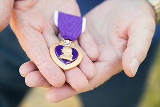 Senior man holding the United States military purple heart medal in his hands