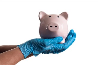 Doctor or nurse wearing surgical gloves holding piggy bank isolated on white