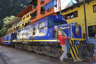 Two tourists at the locomotive of the Perurail in the station