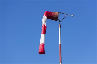 Red and white windsock against blue sky