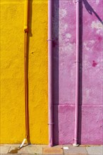 Pink and yellow wall with gutter and cable