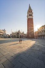 Two tourists stroll lonely through St. Mark's Square
