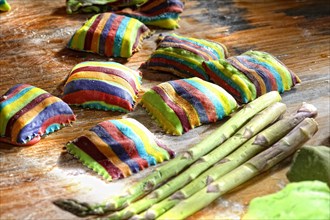 Homemade colorful ravioli on floured wooden table