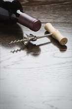 Abstract wine bottle and corkscrew laying on a reflective wood surface with room for text