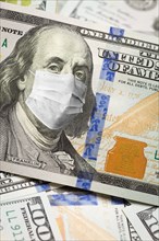 One hundred dollar bill with medical face mask on face of benjamin franklin