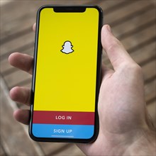 Hand haelt iPhone 11 Pro mit geoeffneter Snapchat App