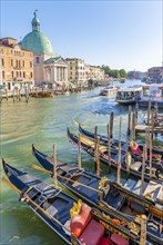Gondolas and boats on the Grand Canal with church San Simeone Piccolo at the Ponte degli Scalzi