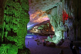 Visitors in large limestone karst cave with stalactite and stalagmite formations
