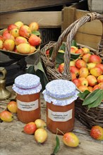 Jars of homemade crabapple jam and crabapple fruit in basket