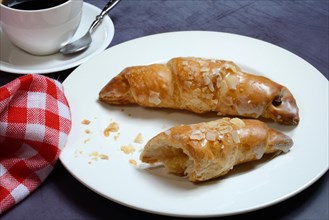 Almond croissant on plate with coffee cup