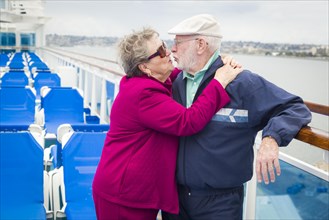 Happy senior couple kissing on the deck of a luxury passenger cruise ship