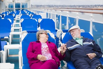 Happy senior couple relaxing on the deck of a luxury passenger cruise ship