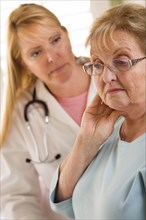 Melancholy senior adult woman being consoled by female doctor or nurse