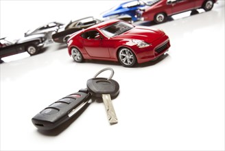 Car keys and several sports cars on white background