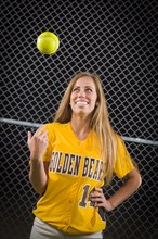 Young female softball player portrait with ball in the air