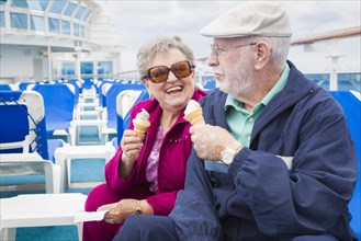Happy senior couple enjoying ice cream on the deck of a luxury passenger cruise ship