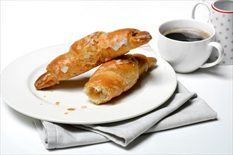 Almond croissant on plate with coffee cup