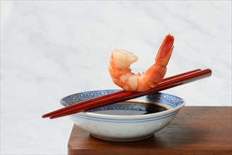 Cooked shrimp on chopsticks and shell with soy sauce