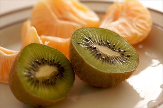 Kiwi and clementine tangerines on a plate in early morning light