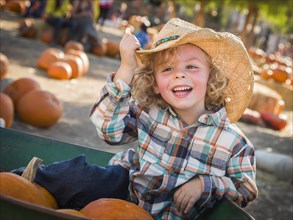 Adorable little boy wearing cowboy hat at pumpkin patch farm