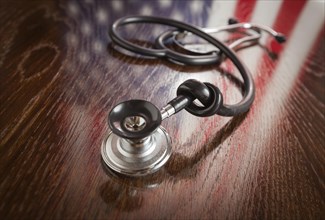 Knotted stethoscope with american flag reflection on wooden table