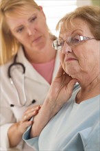 Melancholy senior adult woman being consoled by female doctor or nurse