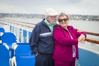Happy senior couple enjoying the view from deck of a luxury passenger cruise ship