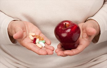 Senior woman holding pills and apple in her palms