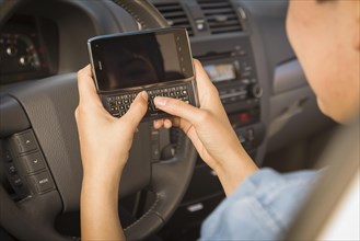 mixed-race woman with smart phone texting and driving