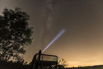 Stargazer under Milky Way with flashlight