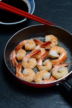 Fried prawns in pan and small bowl with soy sauce