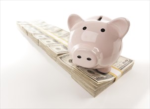 Pink piggy bank on row of hundreds of dollars stacks isolated on a white background