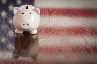Piggy bank with an american flag reflection on wooden table