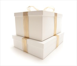 Stacked white gift boxes with gold ribbon and bow isolated on a white background