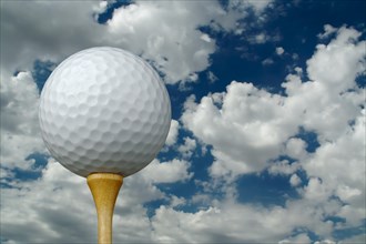 Golf ball & tee with clouds and sky background