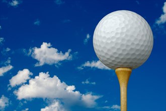 Golf ball & tee with clouds and sky background