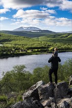 Man with her small baby overlooking the Karasjohka river bordering Norway and Finland