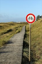 Bicycle prohibition sign with wooden plank path at Kniepsand