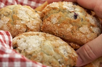 Man's hand grabbbing for blueberry muffins in basket