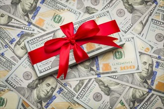 Stack of newly designed U.S. one hundred dollar bills gift wrapped in red bow