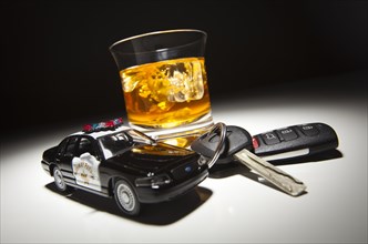 Highway patrol police car next to alcoholic drink and keys under spot light