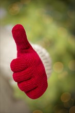 Woman in sweater with seasonal red mittens holding out a thumb up sign with her hand