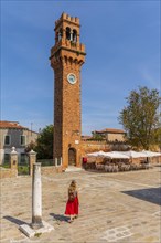 Tourist in red dress in front of St. Stefano bell tower