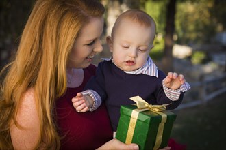 Beautiful young mother and smiling baby with wrapped christmas gift
