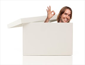 Young man with okay hand signal and popping his head from blank white box isolated on a white background