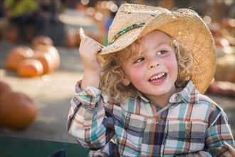 Adorable little boy wearing cowboy hat at pumpkin patch farm