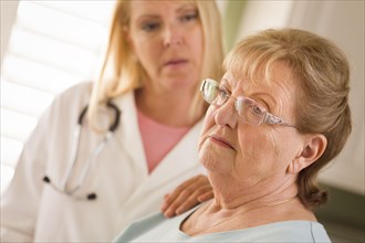 Melancholy senior adult woman being consoled by female doctor or nurse